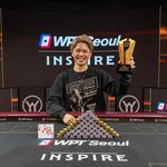 Daisuke Nagano celebrates winning the WPT Seoul 2026 Inspire Superstack, holding his trophy behind a stack of poker chips and his winning ace-king hand.