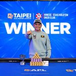 Lester Edoc celebrates his 2026 Taiwan Millions Tournament Main Event victory in Taipei, posing behind stacks of poker chips and his winner's trophy.