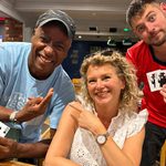 Nuneaton teacher Nicki Kelsall smiles alongside two fellow poker players at a local poker league event, where players show off their cards.