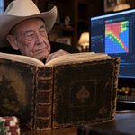 Doyle Brunson looks over an old book to glance at a PC screen showing GTO info.